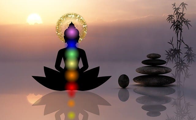 A person sitting in the lotus position with seven chakras on their chest.