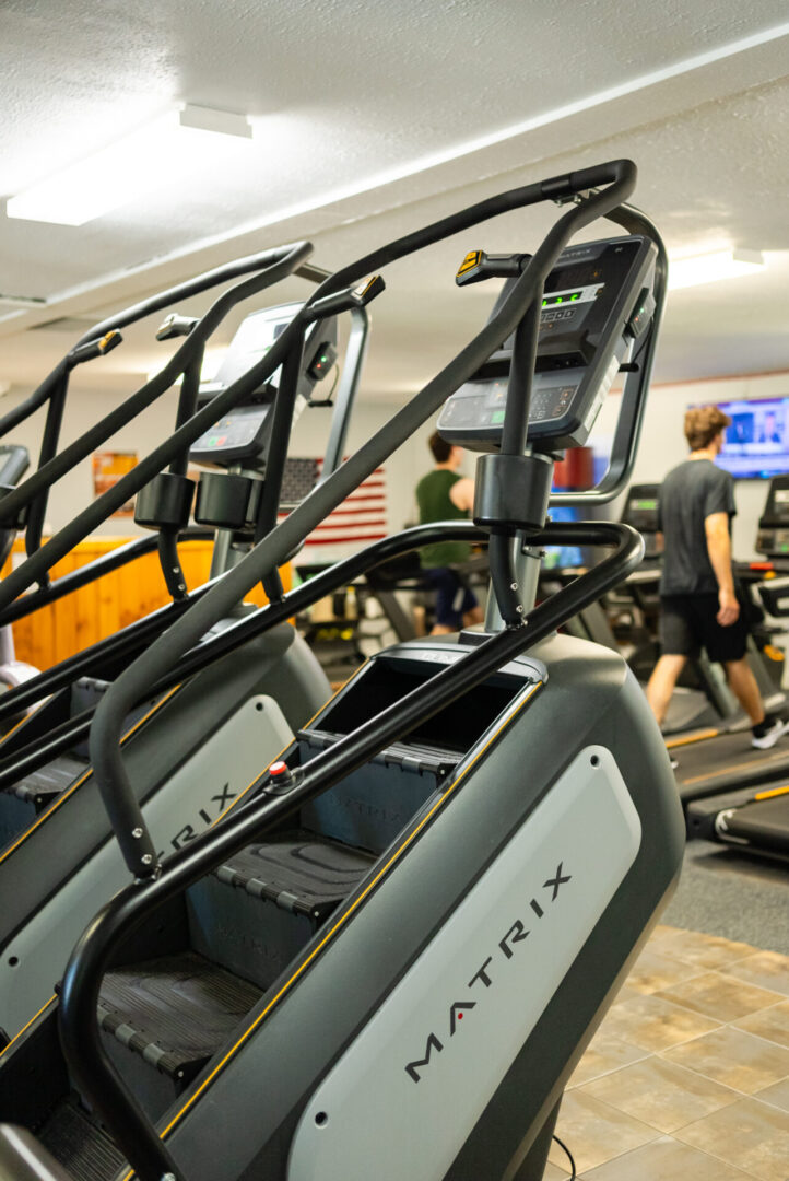 A gym with many machines and people in it