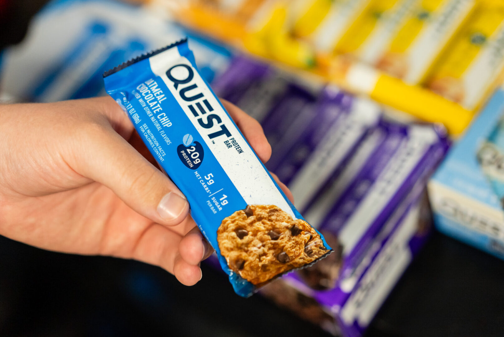 A person holding a bar of quest bars.