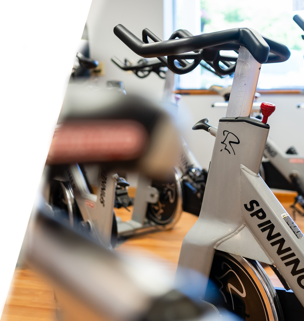 A group of people riding stationary bikes in a gym.