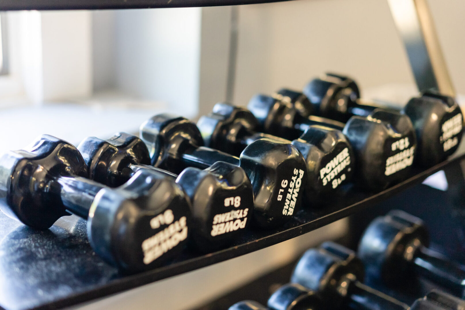 A rack of black dumbbells in the gym.