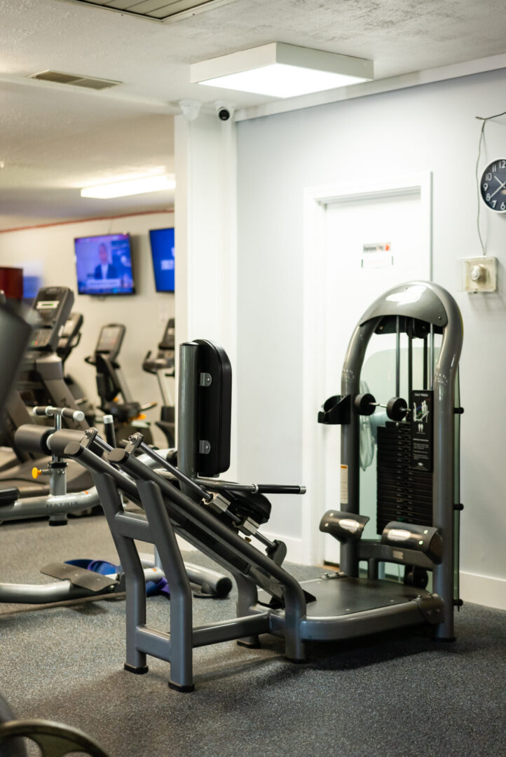 A gym with many machines and a wall clock.