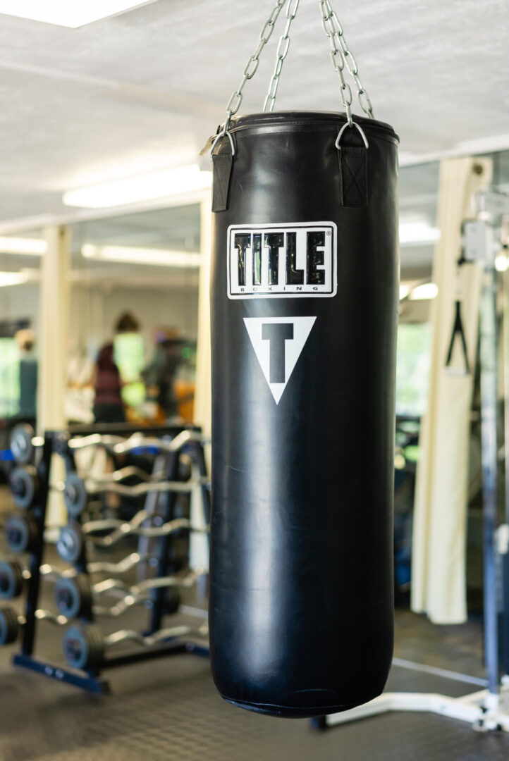 A black punching bag in the middle of a gym.