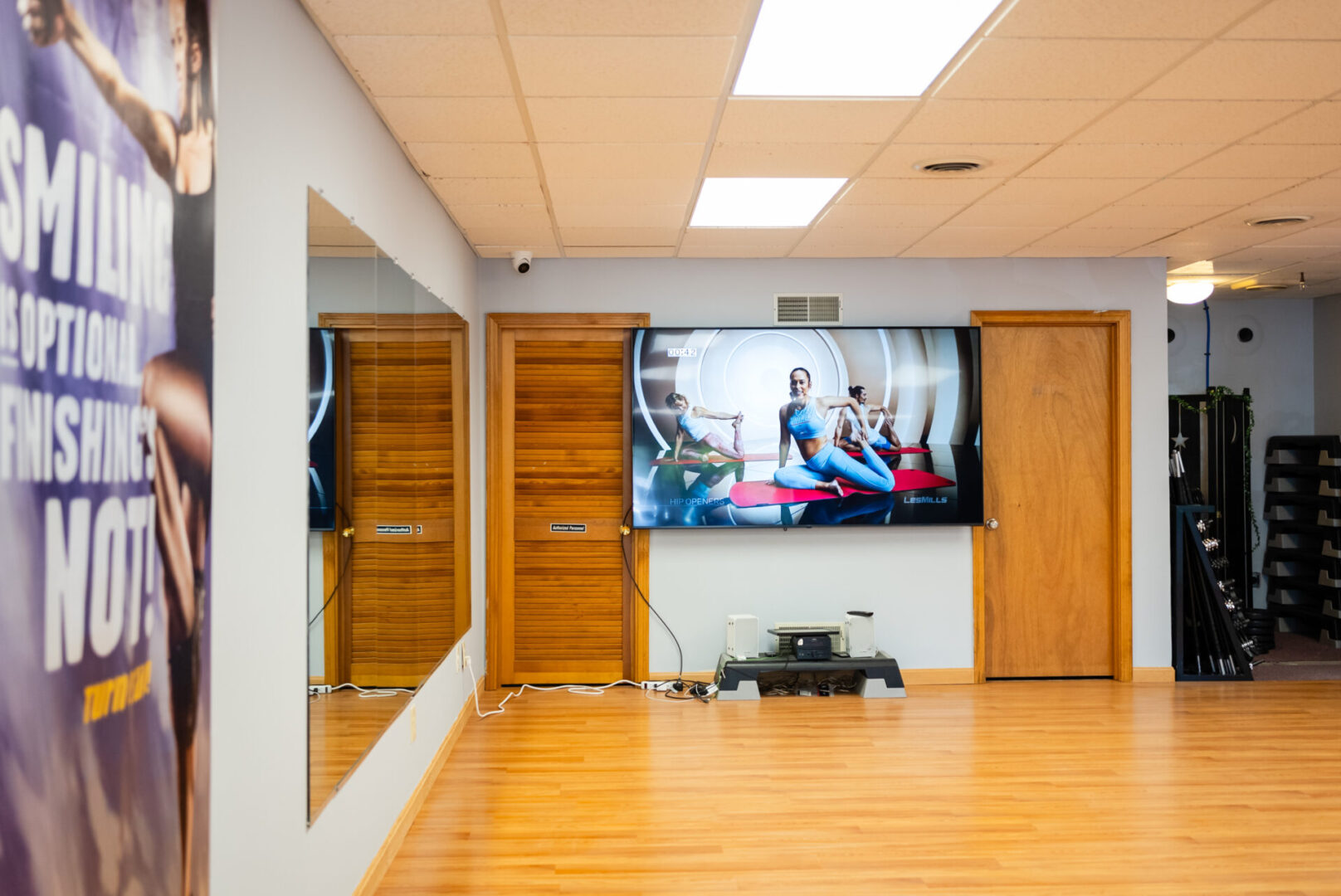 A room with a large tv and wooden floors